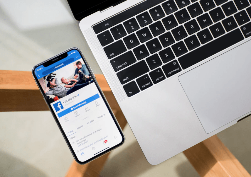 Ways to Repurpose Content with Laptop open and Facebook app open ready to upload content. Keep reading to learn how to convert social media into sales.