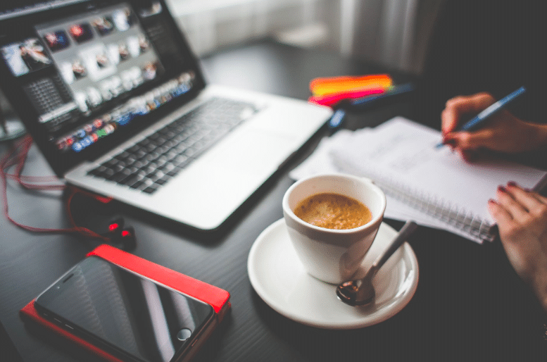 Writing blog headlines on a computer having a cup of coffee