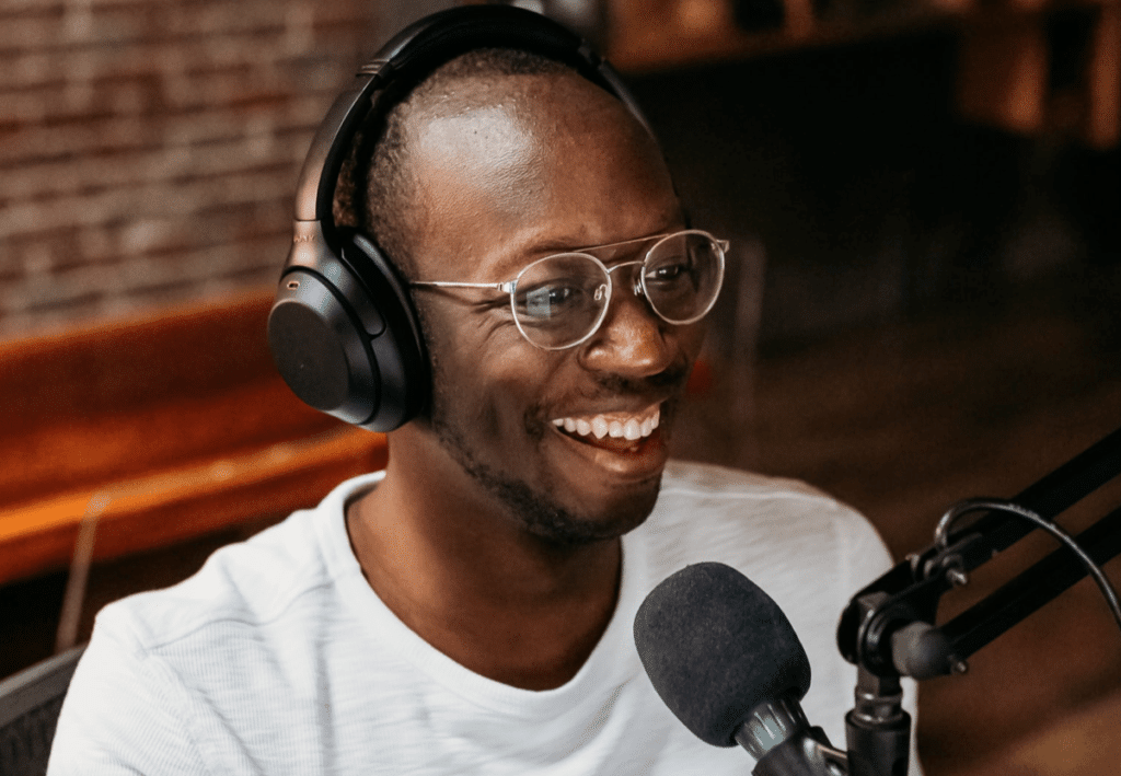 Black guy recording himself with microphone and headphones. He Monetized his blog by starting a podcast