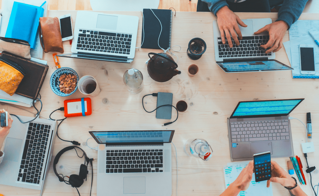 People working on their phone and on the computer. Keep reading to learn about creating an Editorial Content Strategy and content marketing.