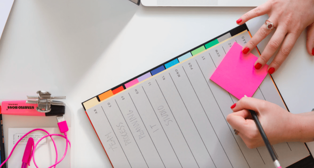 lady writing on pink notepad to help learn how to write a blog post in 30 minutes