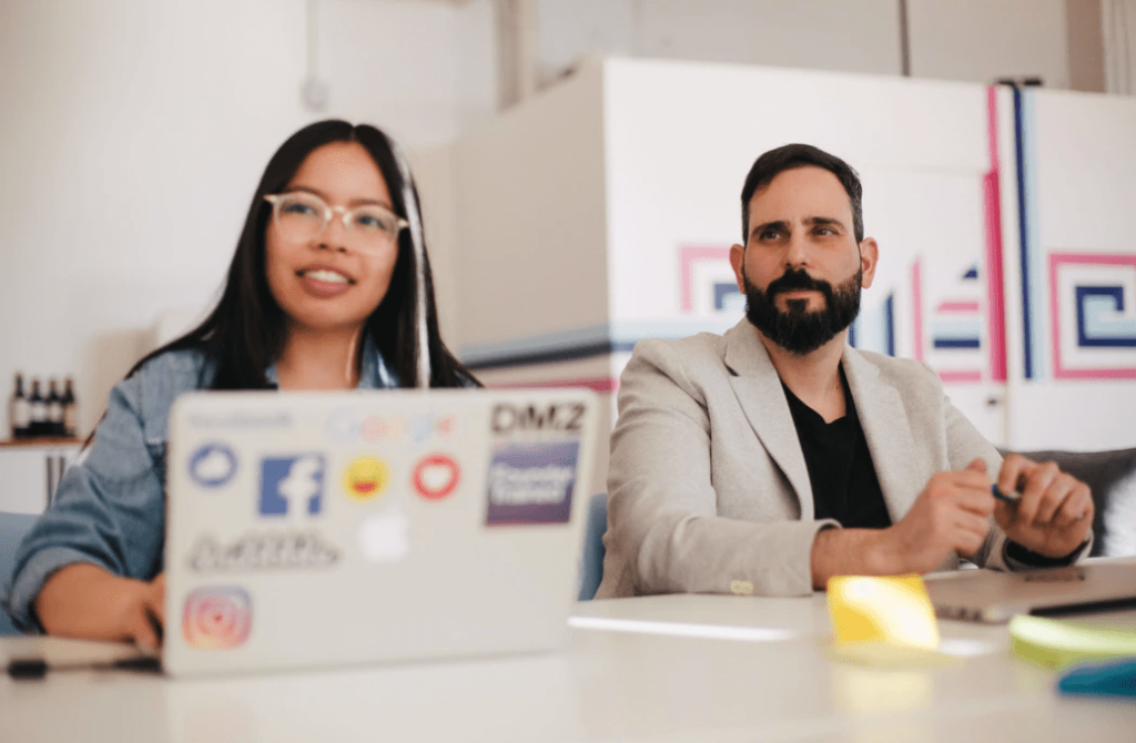 Two marketing professionals sitting in an open office discussing content marketing strategies because content is king.