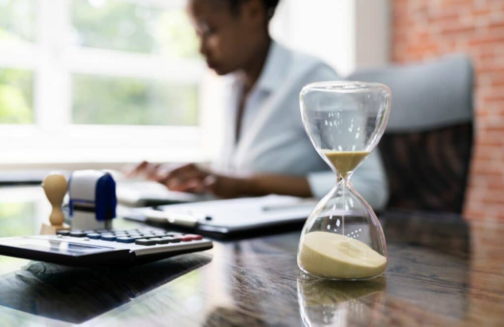 Black woman typing at desk with a timer for productivity. Keep reading to know how to write blog posts faster because content is king.