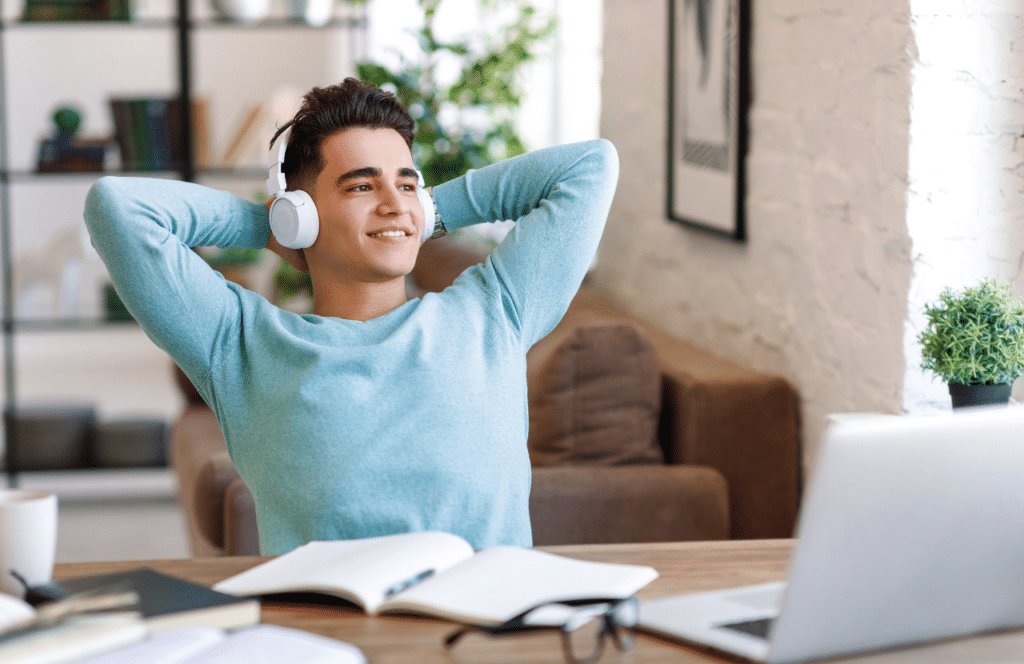 Man sitting in a home office listening classical music to inspire blog writing. Keep reading for tips on how to write blog posts faster.