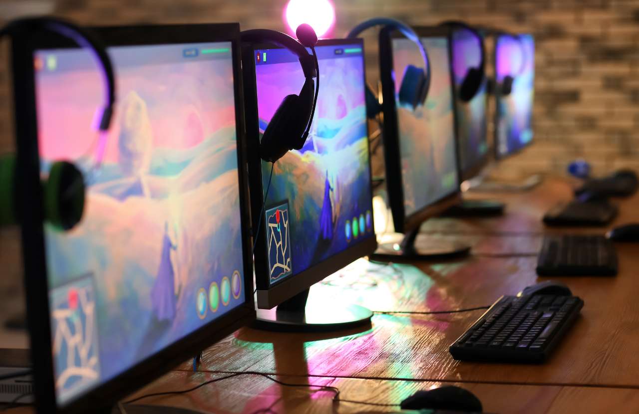 Several desktop computers with bright purple and pinks screens on a long table. Learn more about the future of Blogging here.