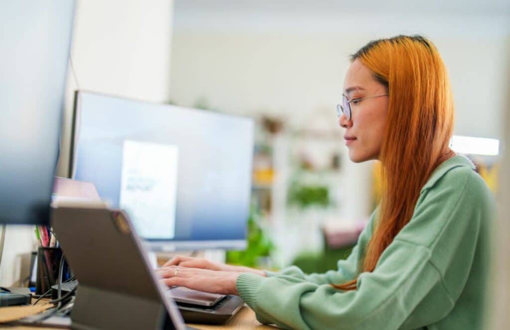 Woman using multiple screens for blogging. Keep reading to know how to write blog posts faster.