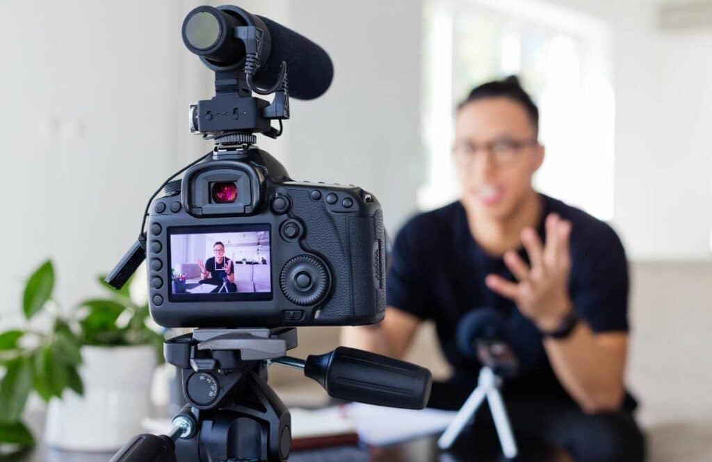 A high quality camera set up focusing on a man with glasses who is recording a video for his blog because content is king