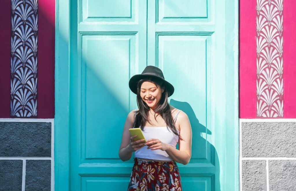 Lady on phone in front of teal door learning How to Make Blog Post Readable. Keep reading to learn where to find blog writers and quality freelance content writers for your blog.