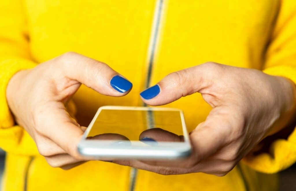 Lady on the phone with blue nail polish working on the best blog post workflow.