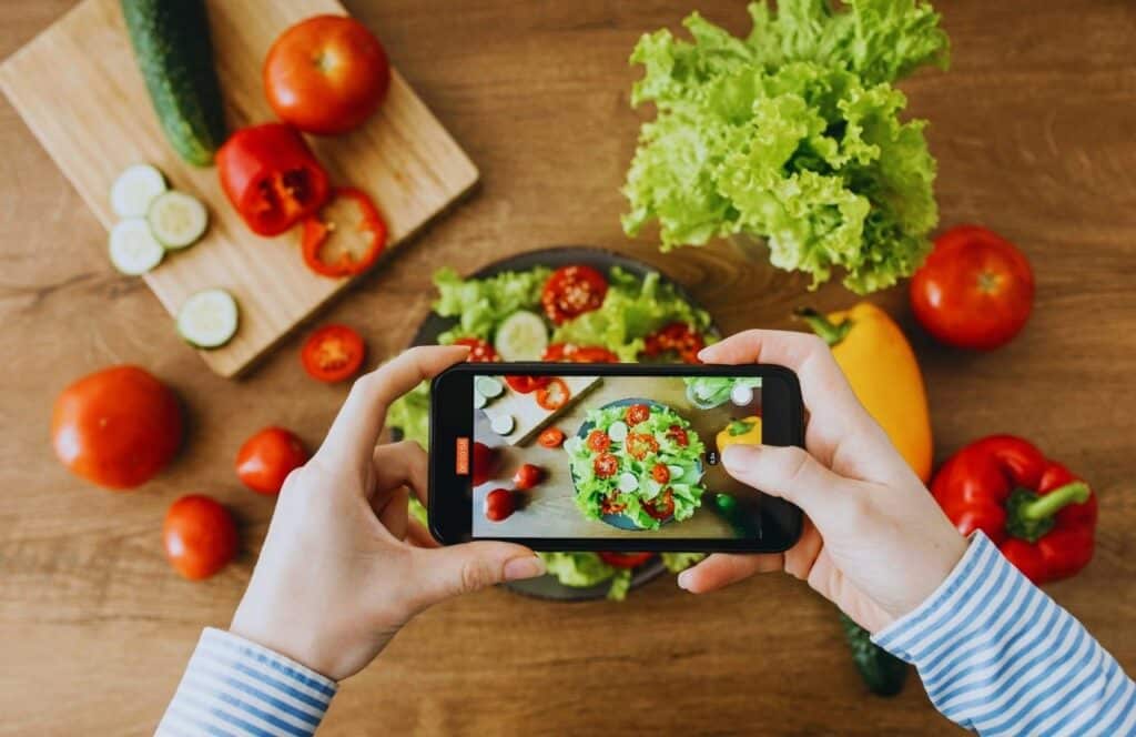 Food blogger taking photos of salad for their blog. Keep reading to know How Much to Charge for a Blog Post