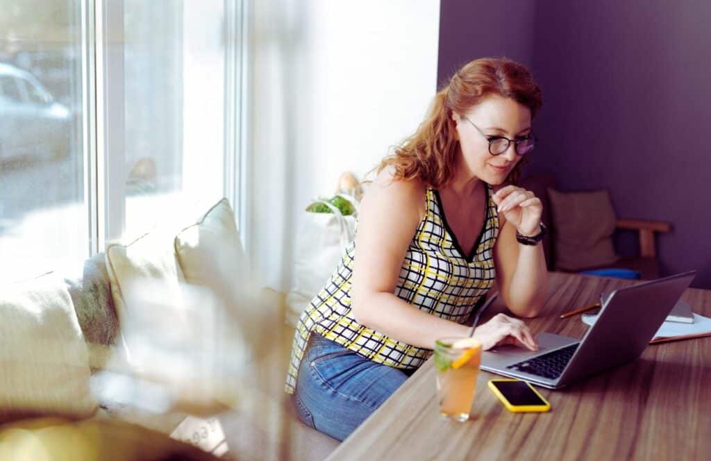 Freelance writer lady working on an article in a coffee shop. Keep reading to know How Much to Charge for a Blog Post