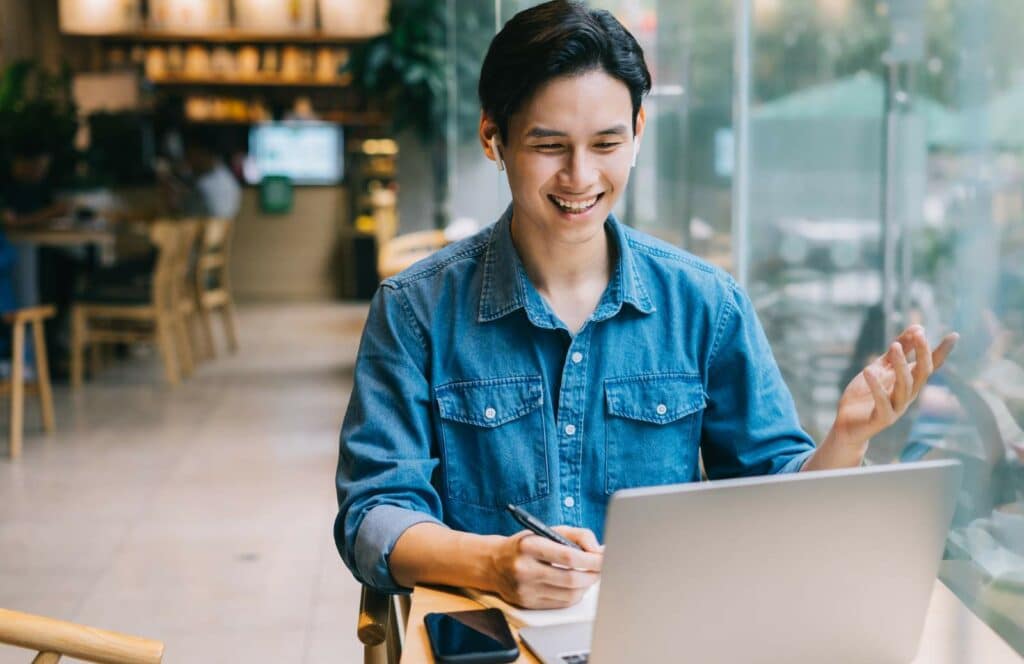 A picture of a man sitting in a coffee shop working on his blog. Keep reading to learn how to monetize your blog from day one.