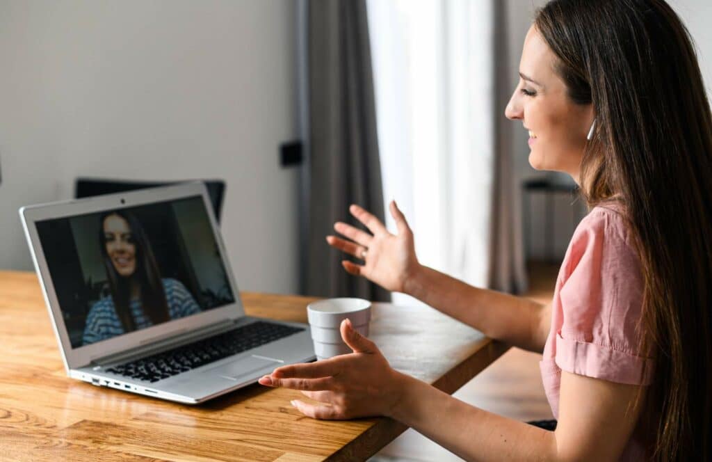 A woman sitting at a table with her laptop meeting with a coaching client as a result of marketing her services on her blog. Keep reading to learn how to monetize your blog from day one.