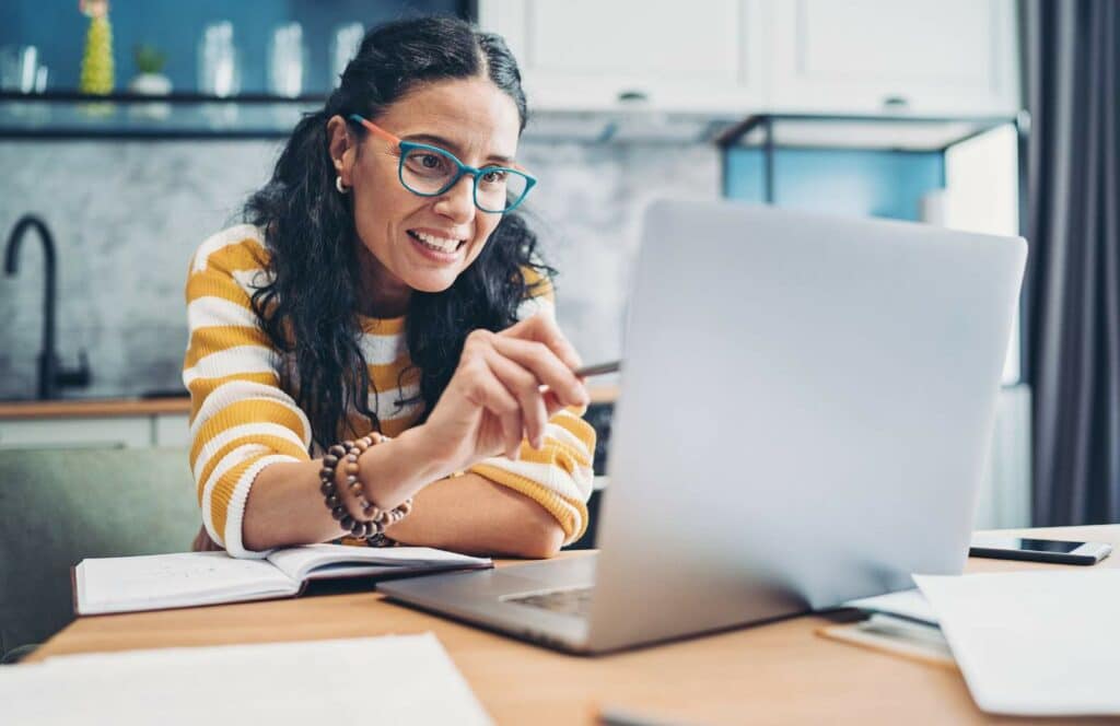 A woman sitting at a table with her laptop reading through premium content on a membership site she has access to. Keep reading to learn how to monetize your blog.