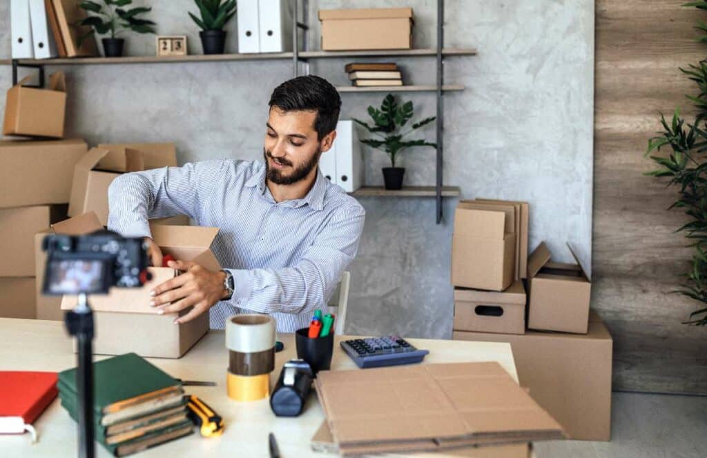 A man sitting at a work table and recording an unboxing for their tech blog. If you have ever asked "What's the point of blogging?" click here to read more.