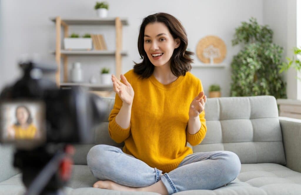 A smiling woman in a yellow sweater sitting on the floor with an inviting presence for blog readers. Learn more about the future of blogging here.