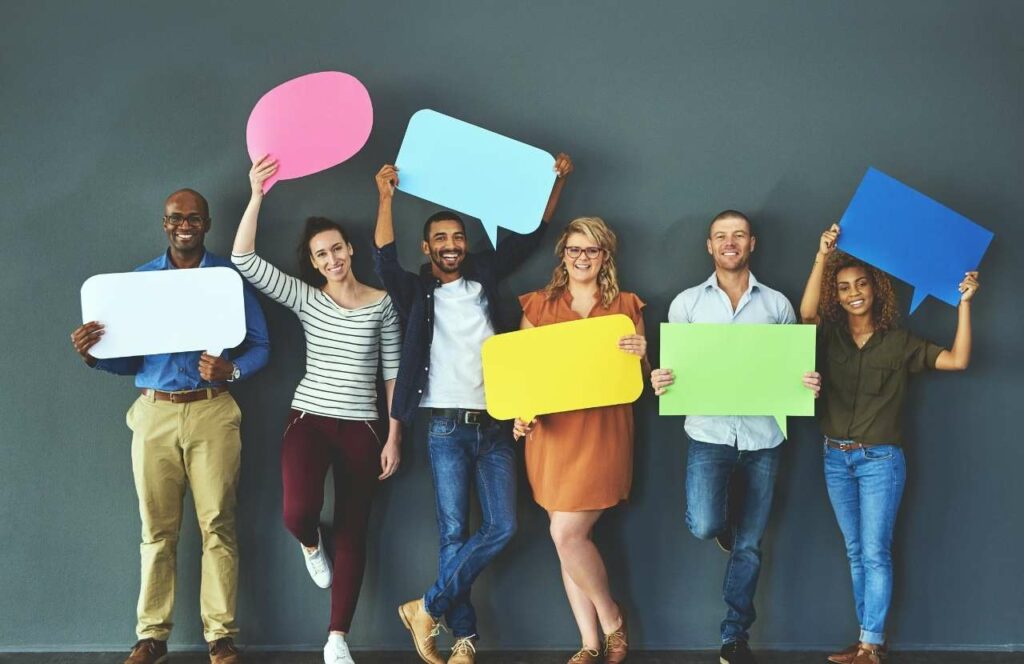 Six people against a wall holding multi-colored comment bubbles representing feedback from blog readers.