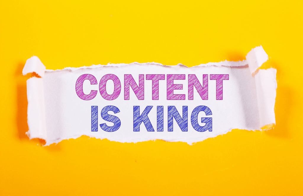The words content is king is behind a ripped yellow piece of paper.