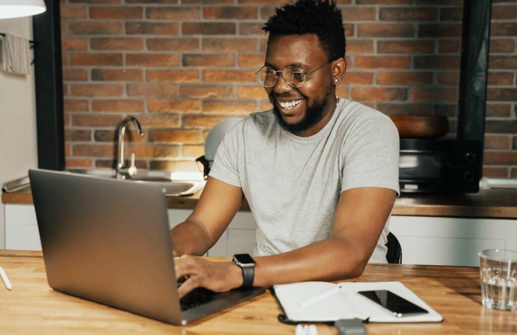 A black man sitting at a table in a kitchen while working on his blog linking strategy. Learn more about internal linking best practices by reading this blog post.