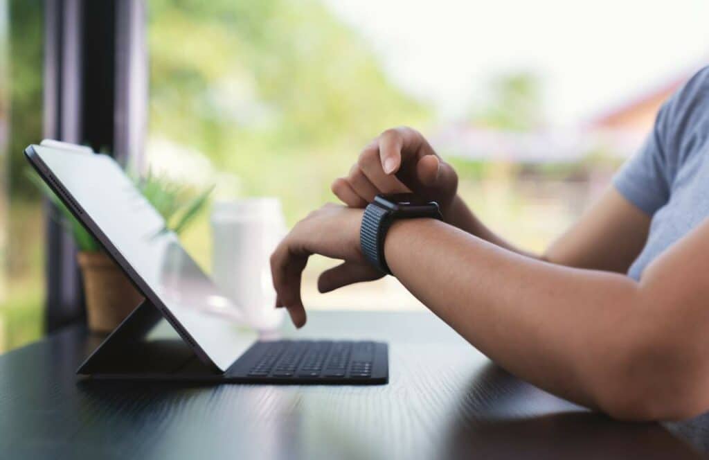 A man looking at his watch as he spends time working on his blog.