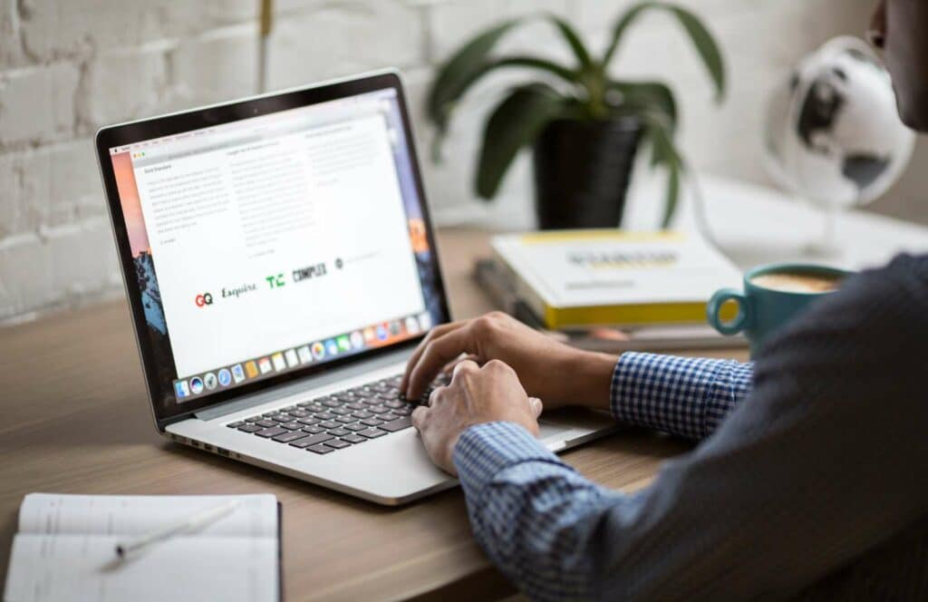 A man sitting at a desk with coffee and books while working on his blog linking strategy. Learn more about internal linking best practices by reading this blog post.