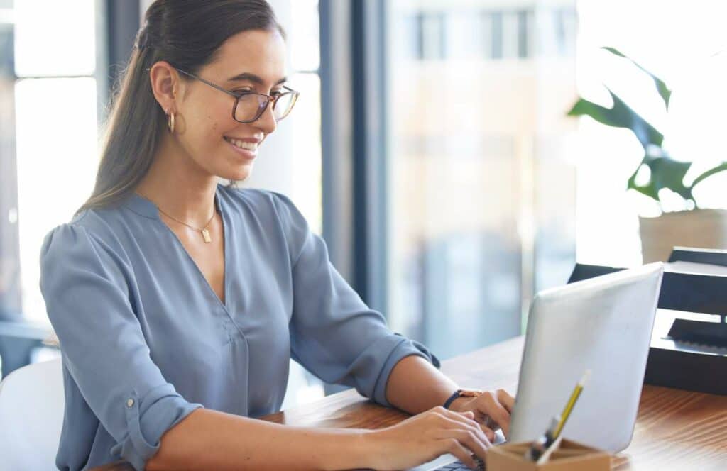 A woman sitting at her computer writing a blog post with an AI blog writer.