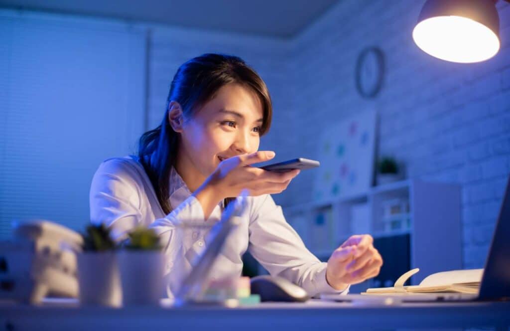 A woman sitting at her desk and talking into her phone.