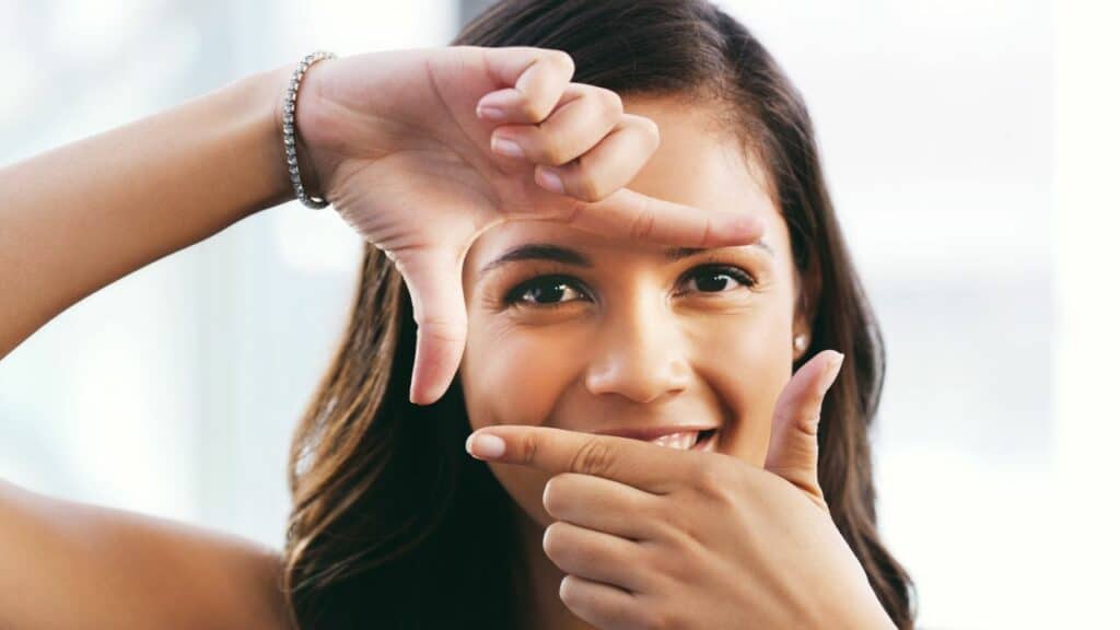 A woman framing her face with her hands. Click here to learn more about affiliate vs partner marketing for bloggers.