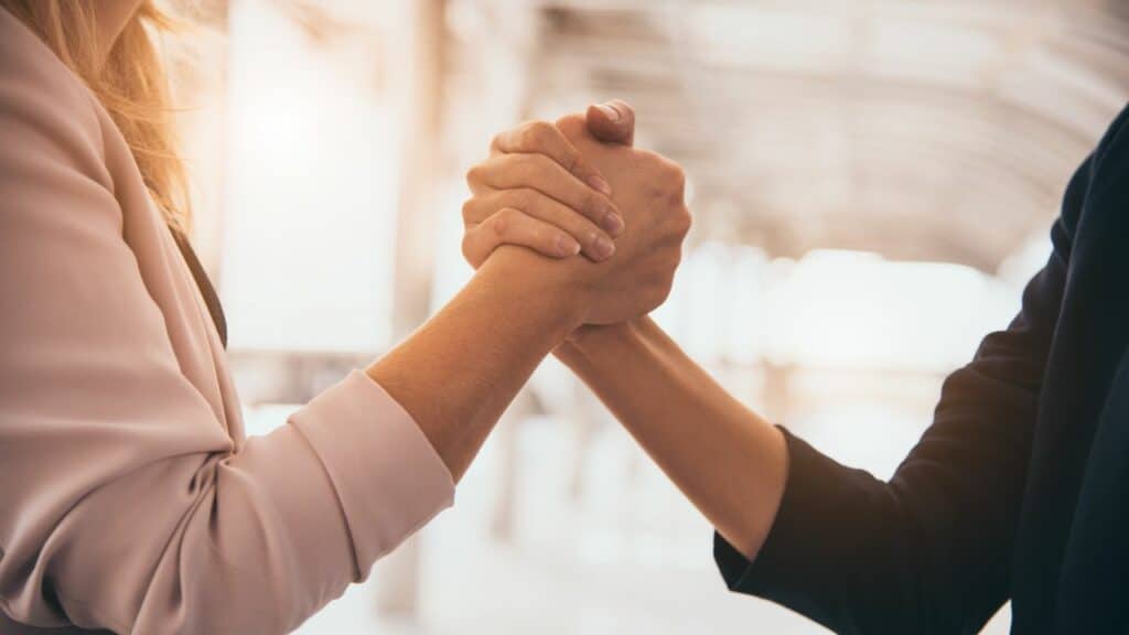 Two professionals shaking hands in agreement, sealing a successful business deal. Click here to learn more about affiliate vs partner marketing for bloggers.