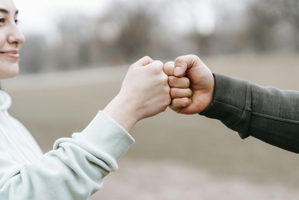 Crop anonymous cheerful woman and man giving fist bump to each other on blurred background of park. Learn more about the future of blogging here.